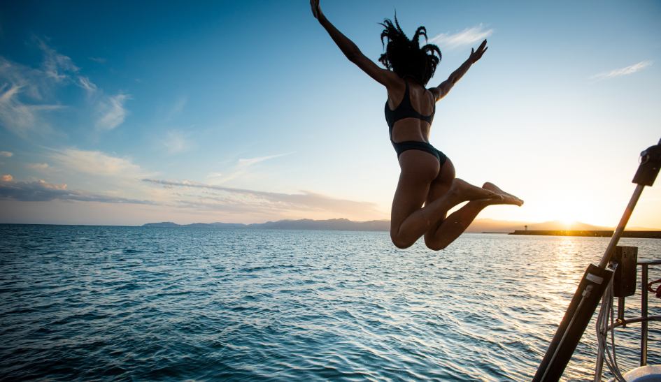 girl in a black swimsuit jumping from the boat into the sea